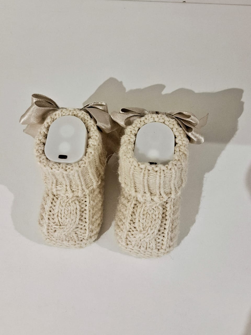 Knitted baby boots adorned with a ribbon at the back.