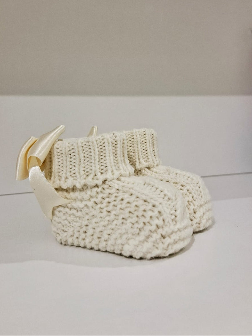 Knitted baby boots adorned with a ribbon at the back.