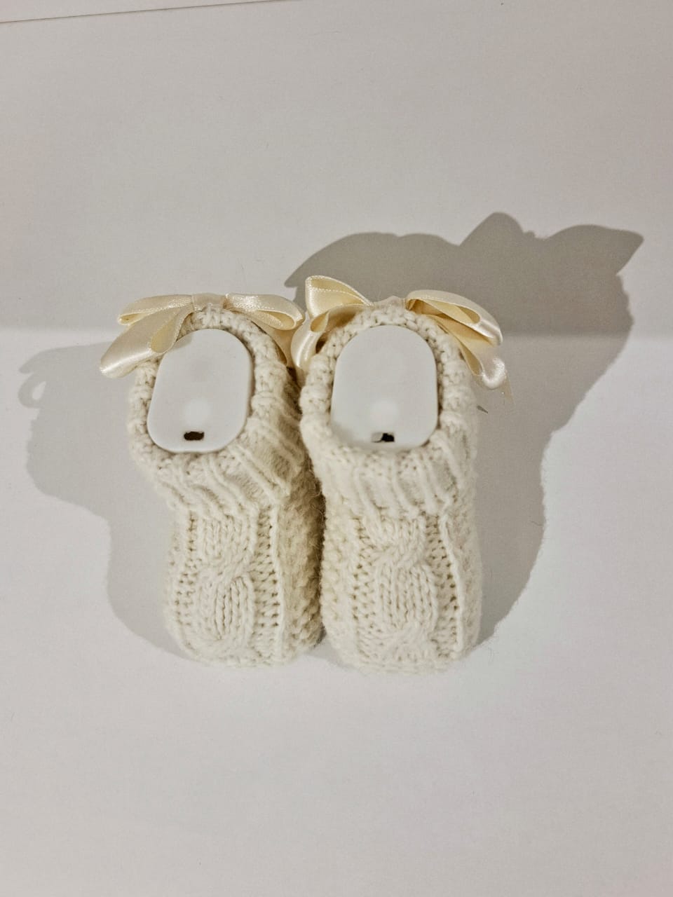 Knitted baby boots adorned with a ribbon at the back.