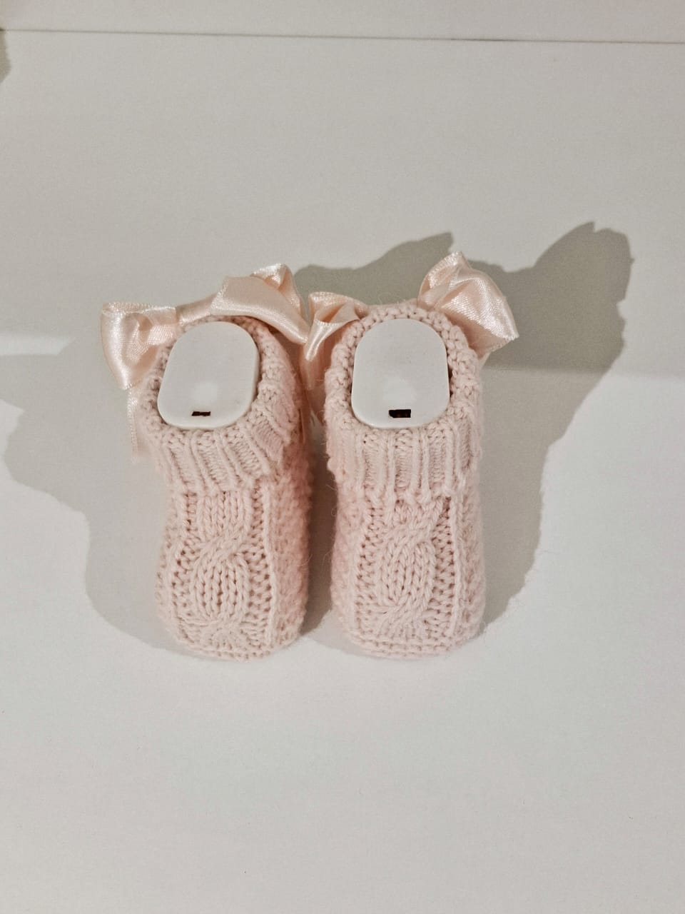 Knitted baby boots adorned with a ribbon at the back.